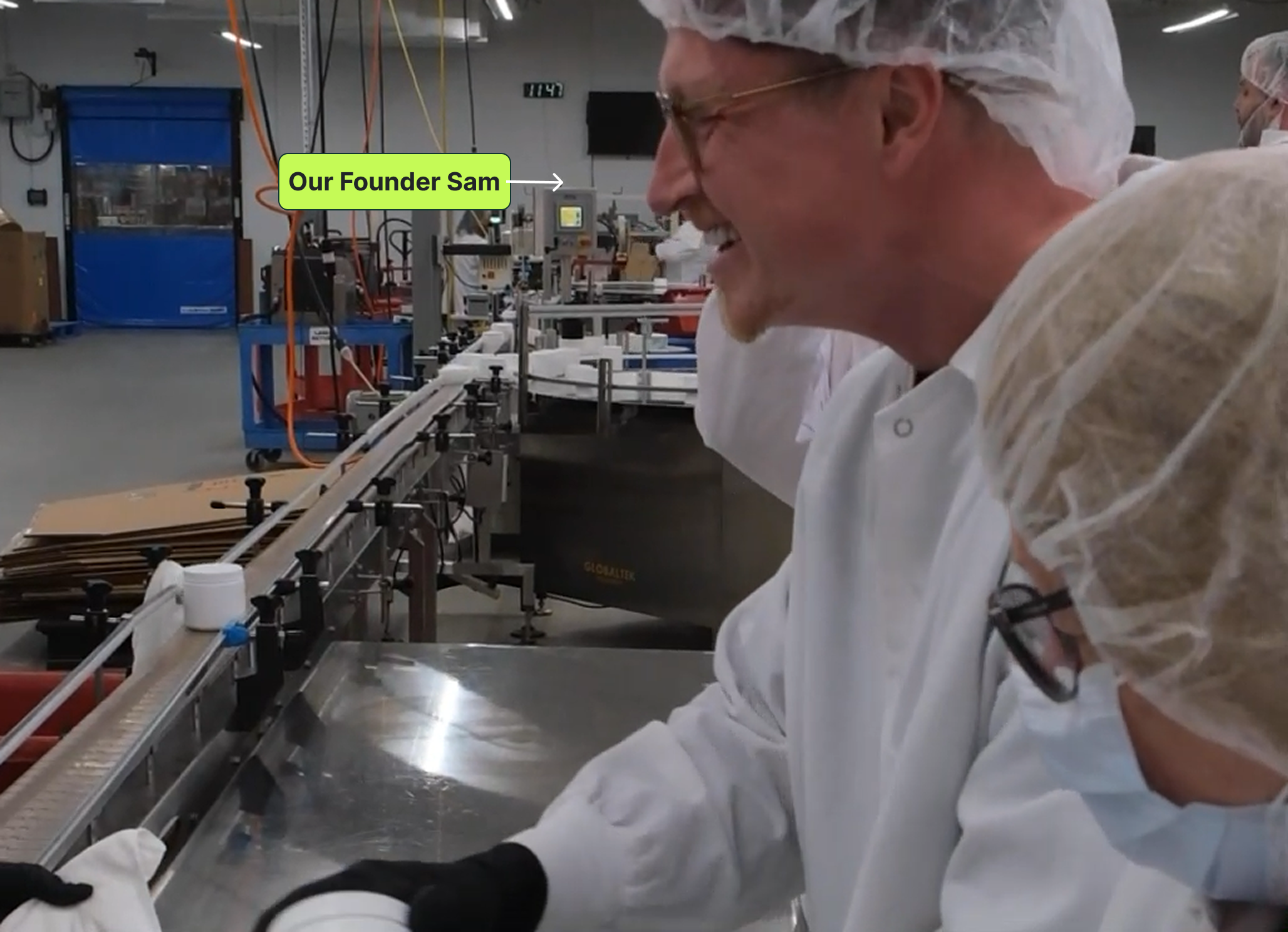 Two workers in protective gear inspecting products on a production line in a factory